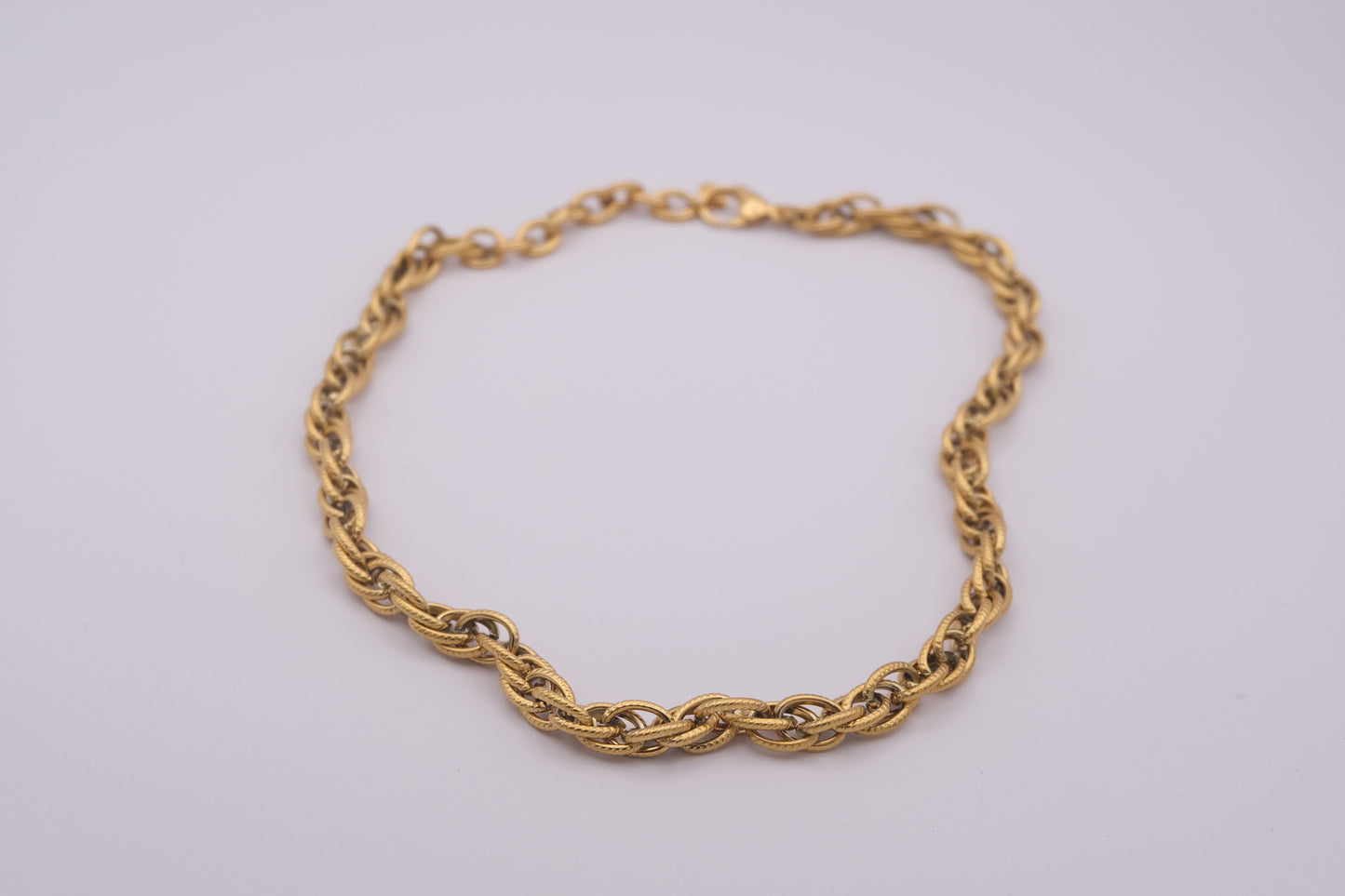 Collar de eslabones dorado "The Esencial Link" sobre fondo blanco.
