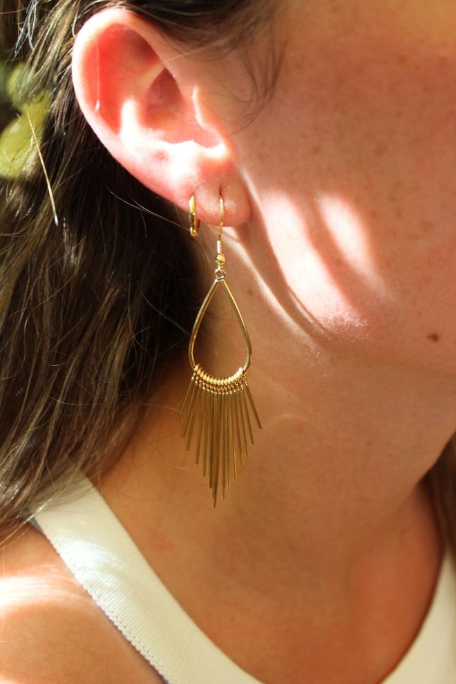 Pendientes Piña Twist puestos en la oreja con luz cálida natural.