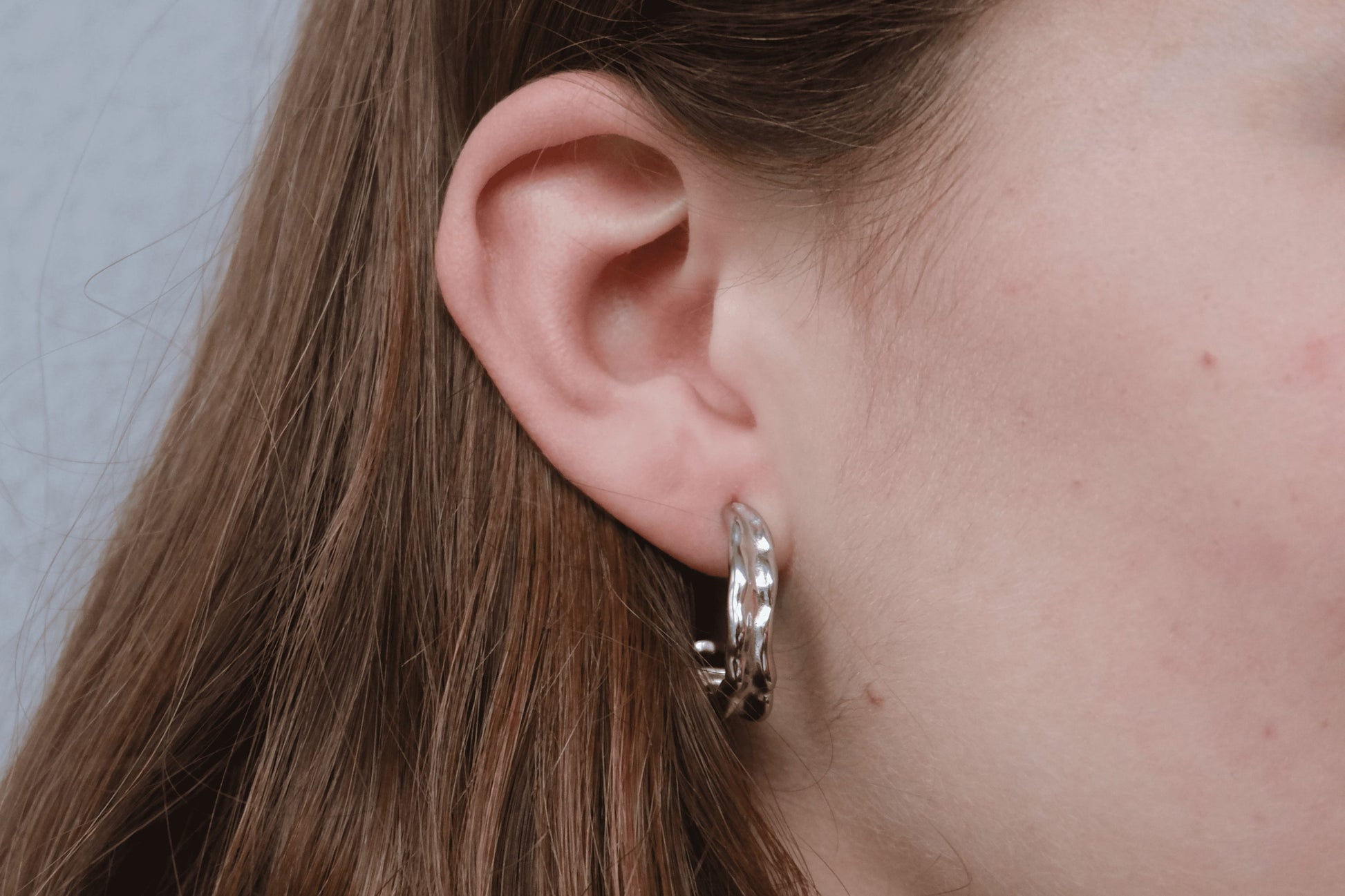 Pendientes plateados "The Spark Drop" lucidos por una modelo.