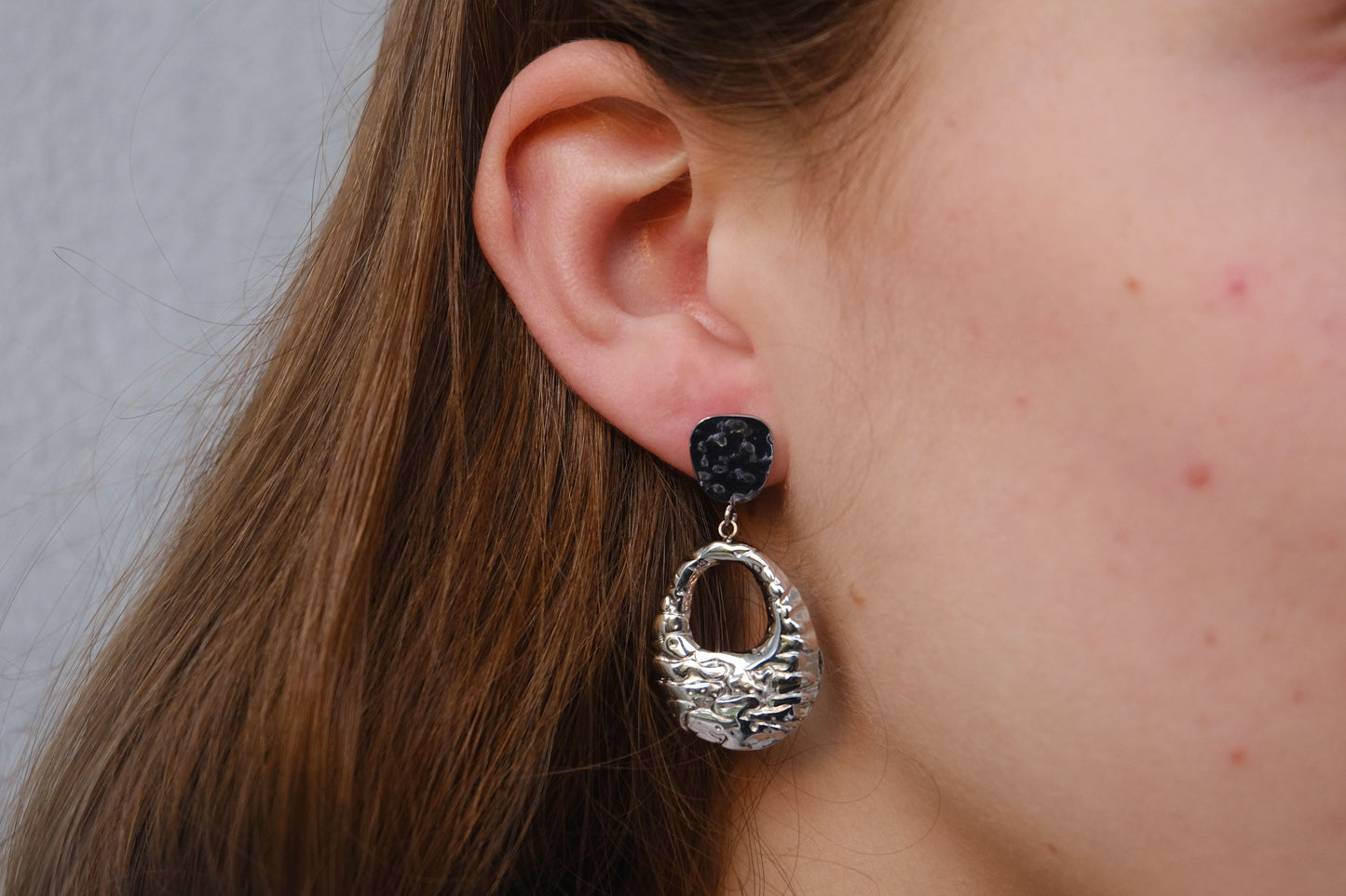 Pendientes plateados "The Shopping Glow" lucidos por una modelo.