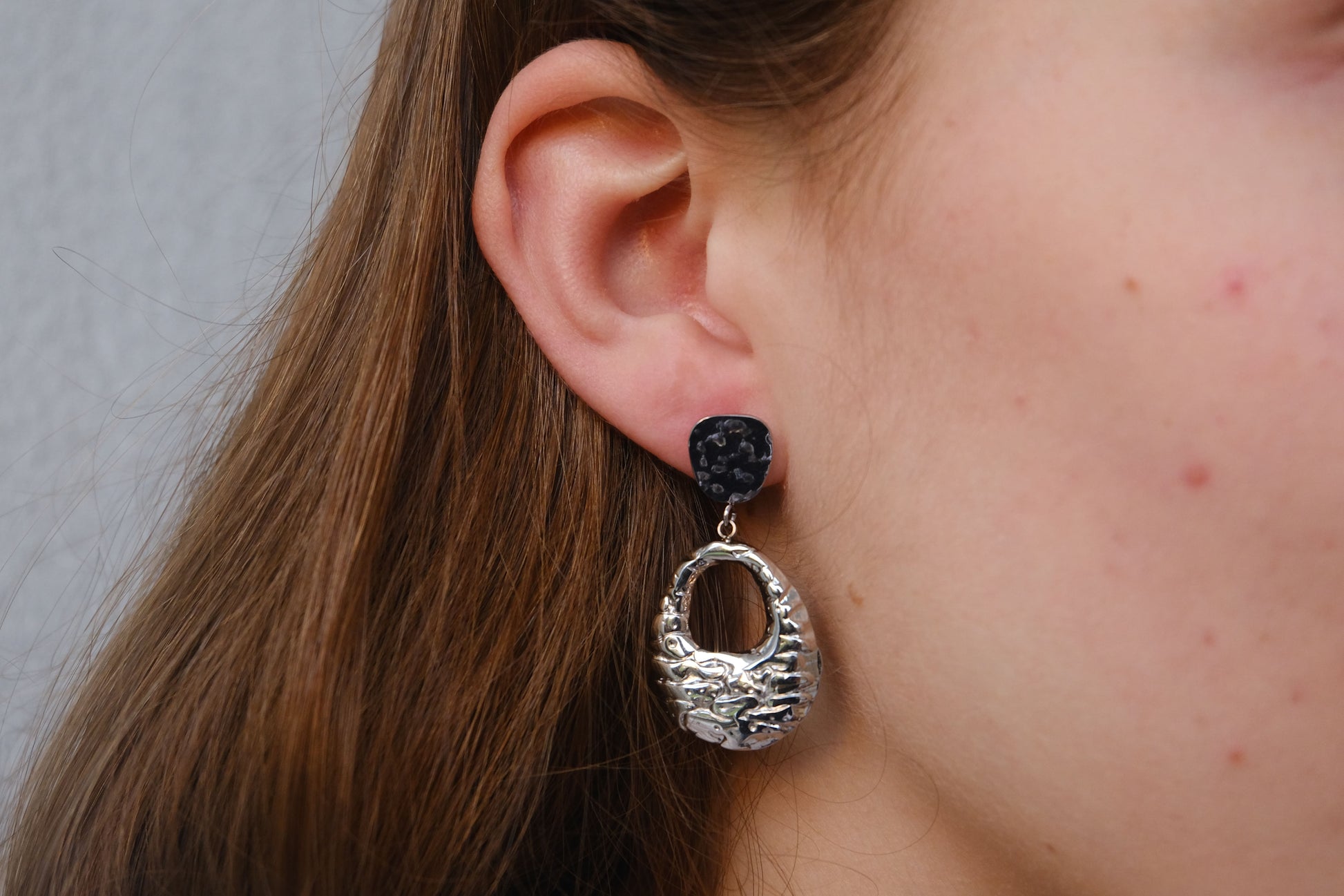 Pendientes plateados "The Shopping Glow" lucidos por una modelo.