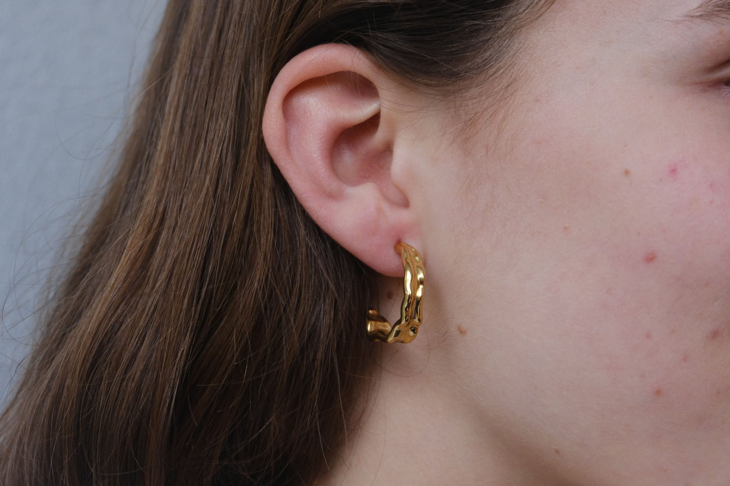 Pendientes dorados "The Spark Drop" lucidos por una modelo.