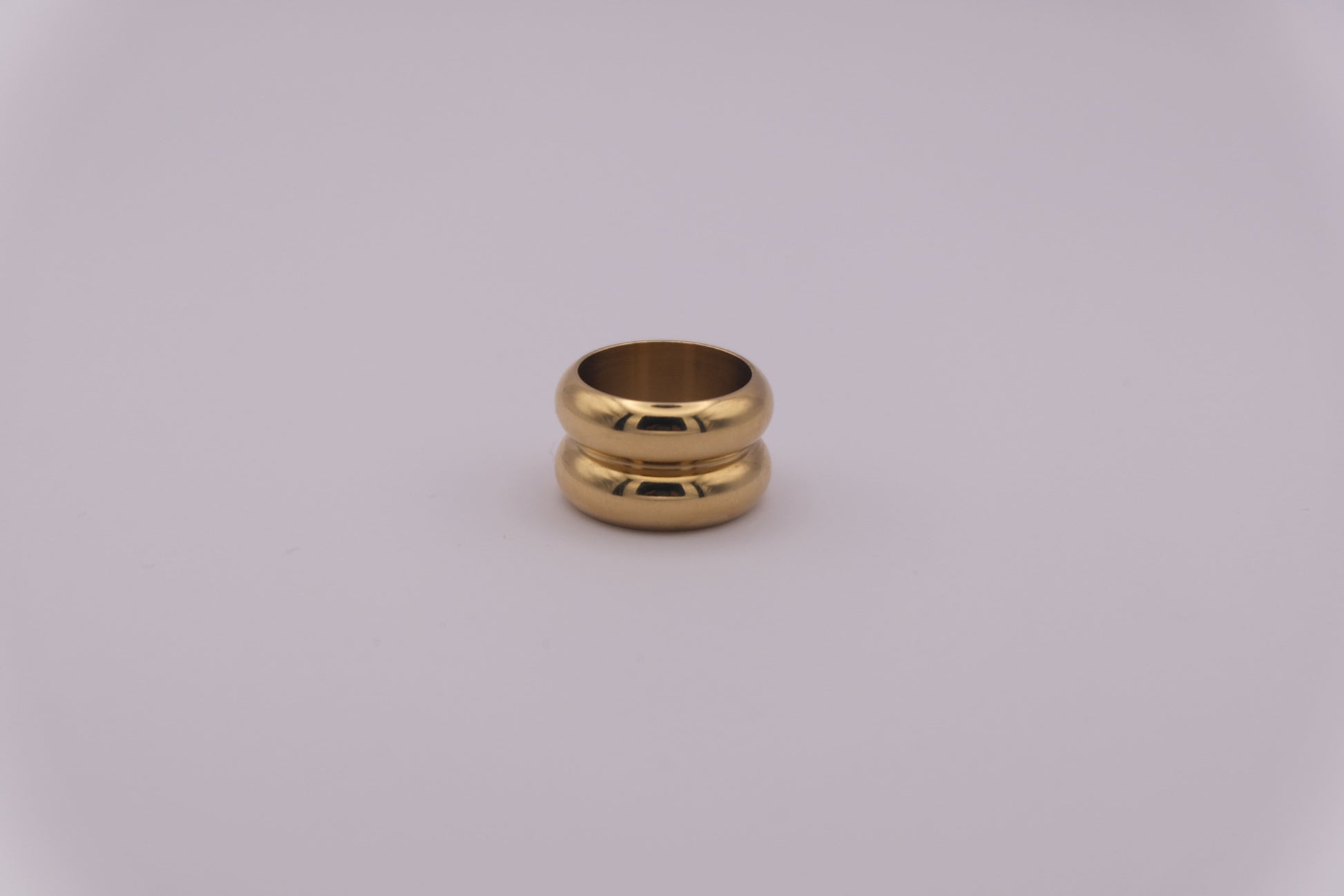 Anillo dorado con textura ondulada "The Morning Flow" sobre fondo blanco.
