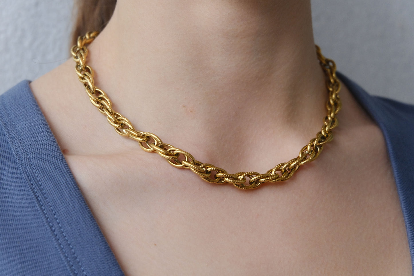 Collar dorado "The Esencial Link" lucido en el cuello de una modelo.