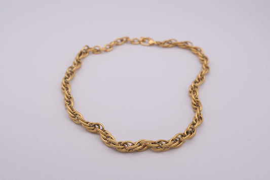 Collar de eslabones dorado "The Esencial Link" sobre fondo blanco.
