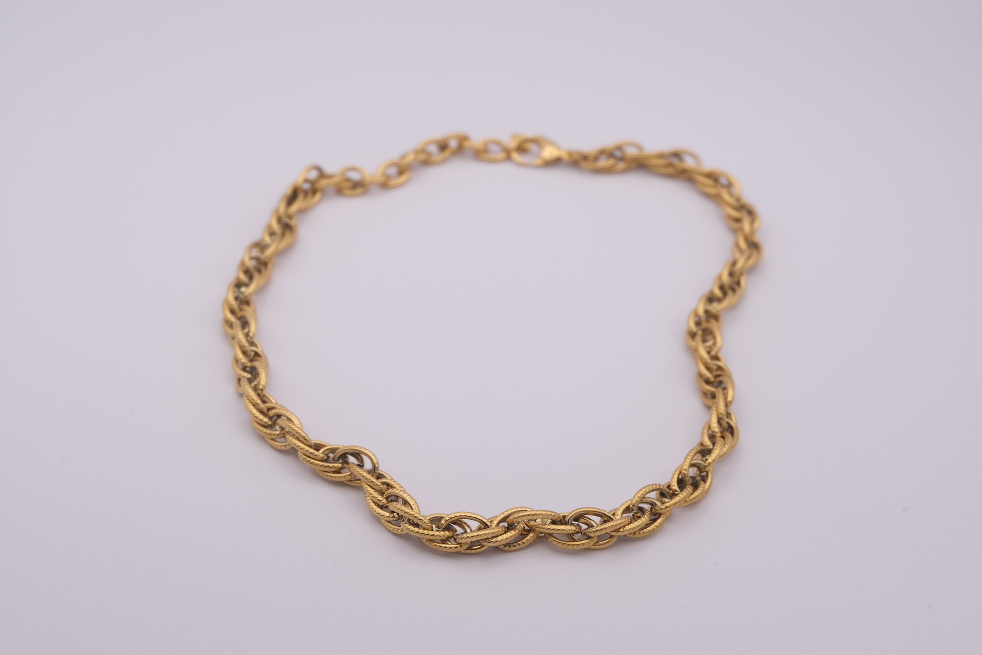 Collar de eslabones dorado "The Esencial Link" sobre fondo blanco.