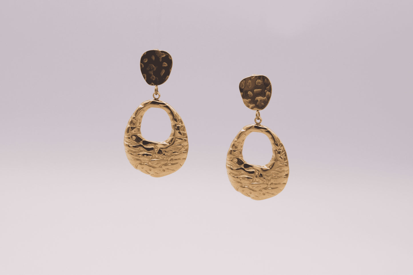 Pendientes dorados "The Shopping Glow" sobre fondo blanco.