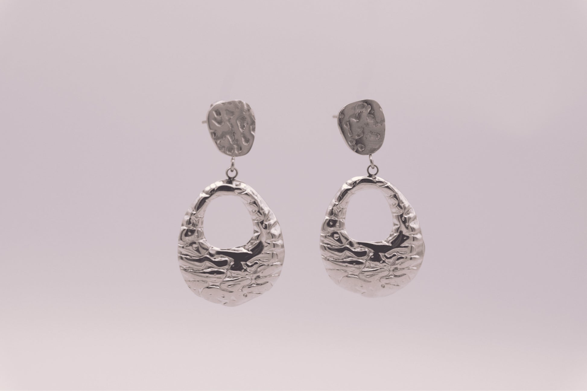 Pendientes plateados "The Shopping Glow" sobre fondo blanco.