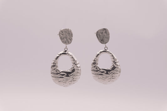 Pendientes plateados "The Shopping Glow" sobre fondo blanco.