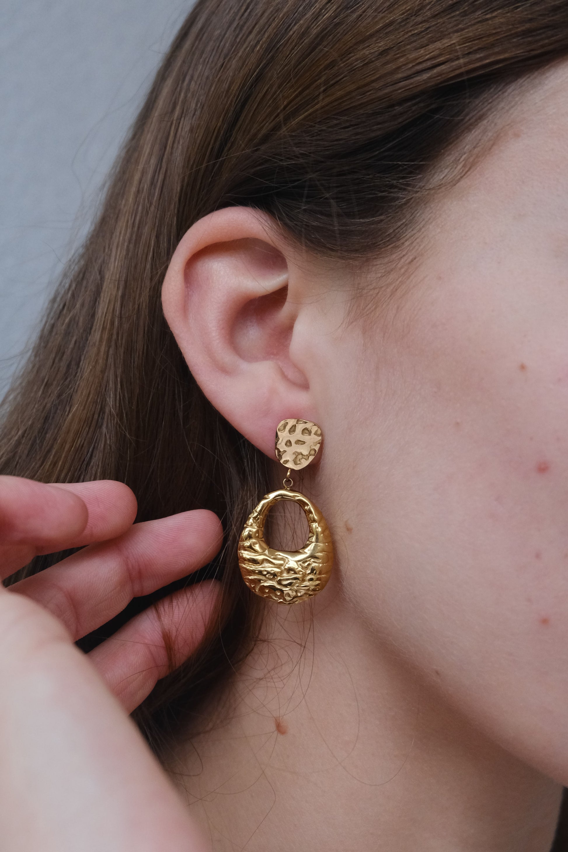 Visión lateral pendientes dorados "The Shopping Glow" en una modelo.