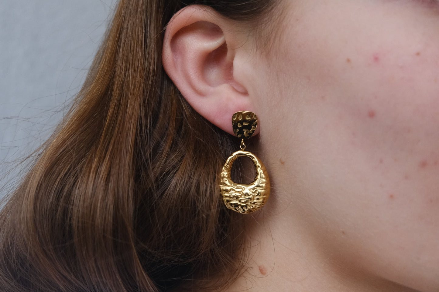 Pendientes dorados "The Shopping Glow" lucidos por una modelo.