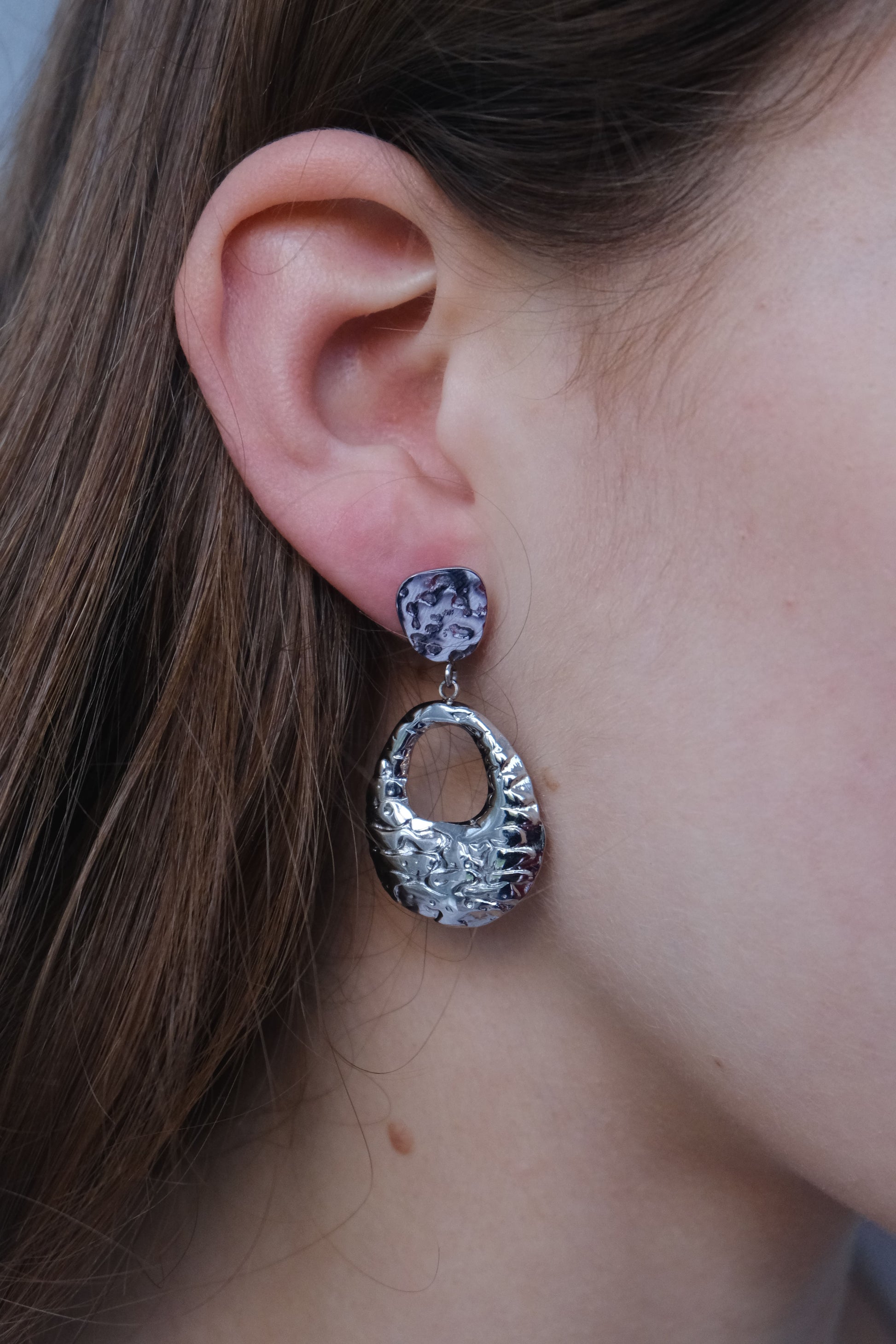 Visión lateral pendientes plateados "The Shopping Glow" en una modelo.