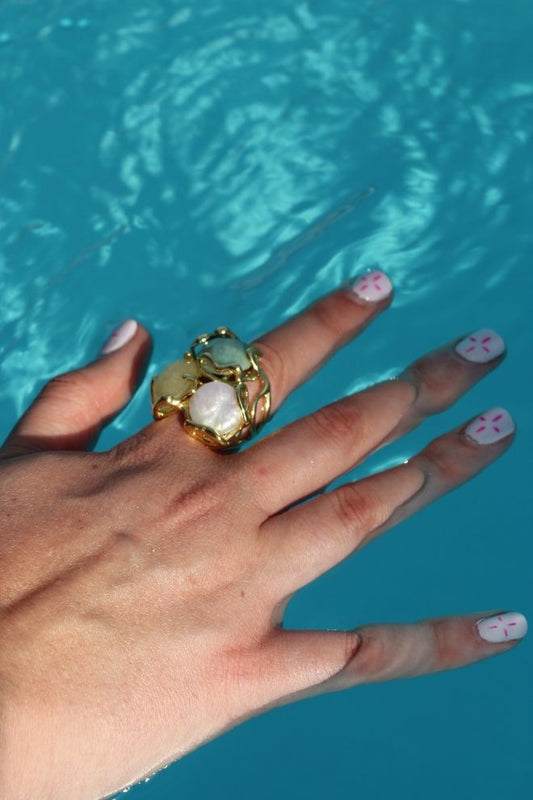 Mano con el Anillo Coco Blanco junto a una piscina, resaltando sus colores vivos.