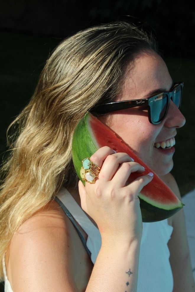 Mujer con el Anillo Coco Blanco sujetando una rodaja de sandía, estilo veraniego y natural.