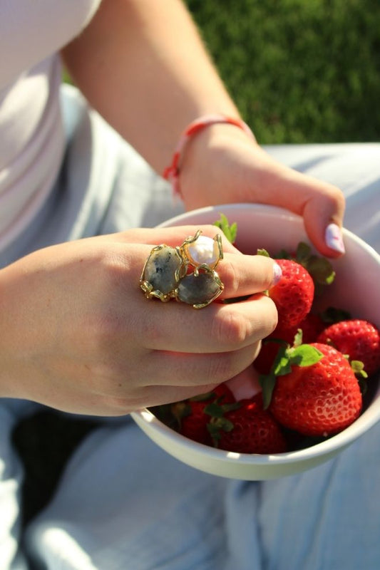 Anillo Perla Nube en la mano de una mujer sujetando un cuenco de fresas, al aire libre en un entorno natural