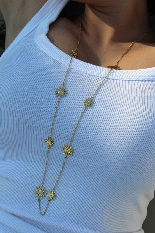 Mujer luciendo el Collar Brillo Tico con top blanco, estilo veraniego.