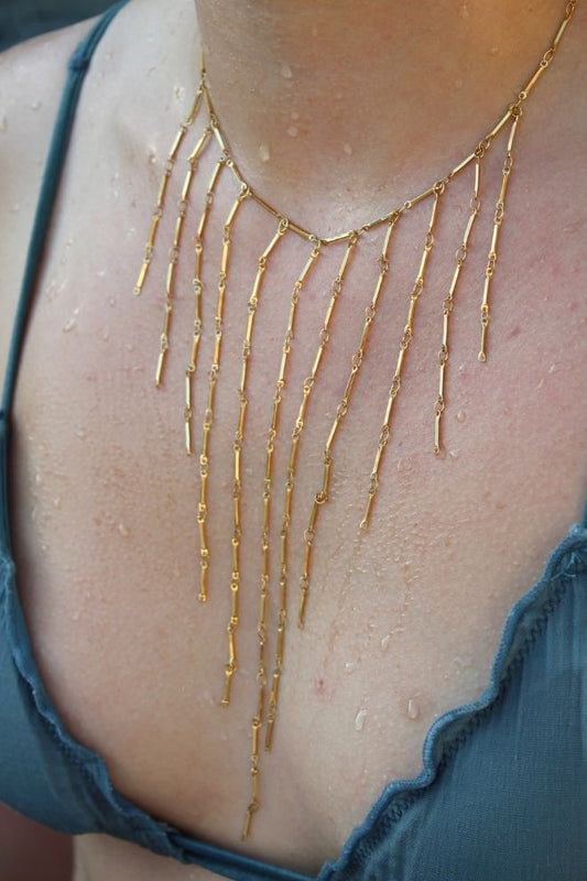 Collar Cascada Coral lucido sobre el pecho con gotas de agua, ideal para verano