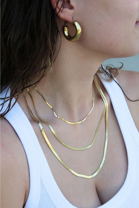 Collar Olas Doradas puesto sobre el cuello, en combinación con pendientes dorados.