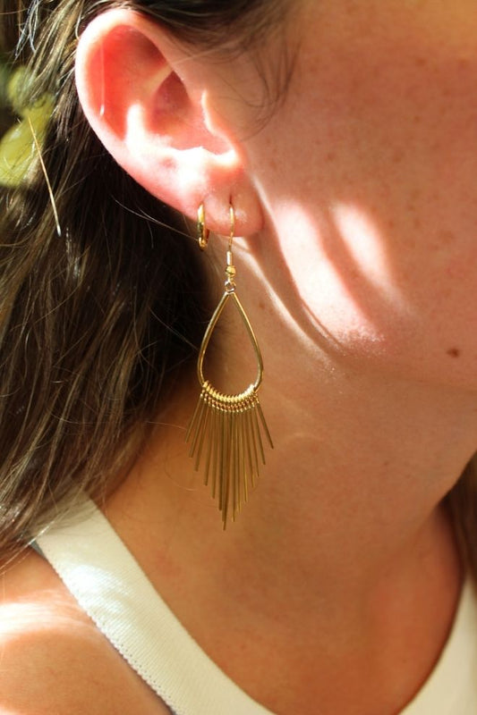 Pendientes Piña Twist puestos en la oreja con luz cálida natural.
